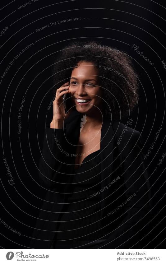 Smiling ethnic woman with smartphone in black studio using smile happy positive online mobile hispanic female young gadget device cheerful social media