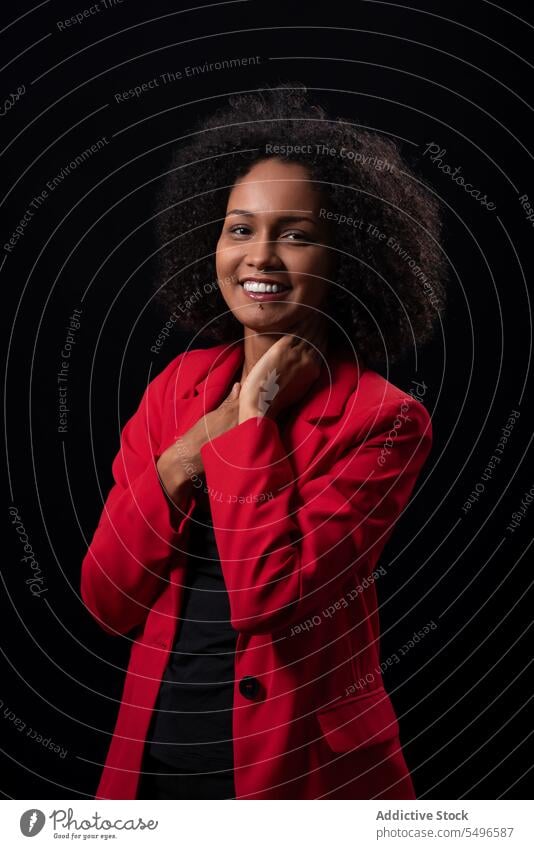 Smiling ethnic woman in red trendy outfit coat contemplate millennial model style confident afro appearance female young hairstyle curly hair individuality lady