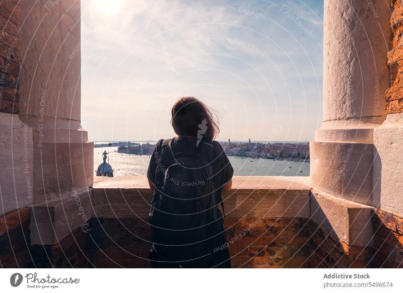 Anonymous female tourist admiring aged city during vacation woman canal architecture admire traveler sightseeing historic terrace wanderlust trip long hair