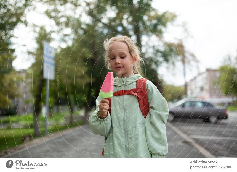 Happy kid with backpack standing on sidewalk and enjoying ice cream child street smile happy cheerful cute childhood car girl adorable summer sweet carefree
