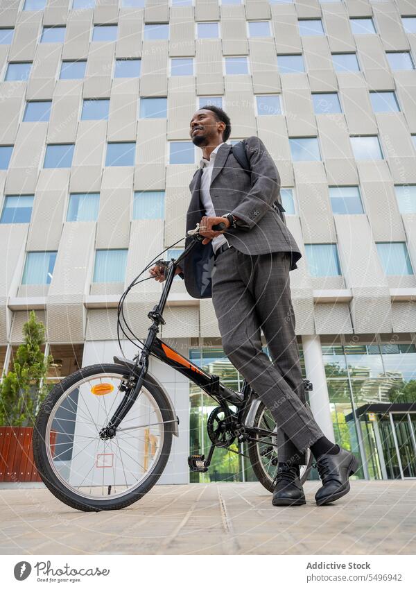 Ethnic entrepreneur with bicycle against contemporary building businessman employee formal elegant executive commute transport male ethnic well dressed black