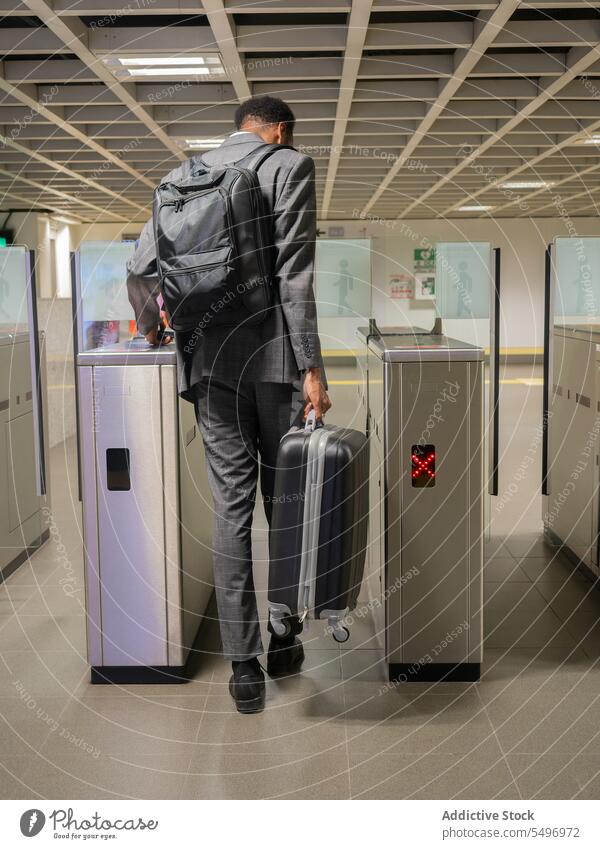 Black businessman with baggage in metro pedestrian suitcase underground subway pass card tourniquet male black african american entrepreneur passenger