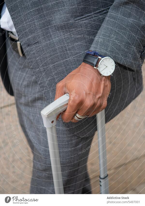 Unrecognizable black businessman with suitcase on street commute entrepreneur luggage wristwatch baggage trip handle formal pavement walk ethnic well dressed