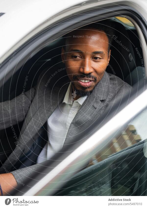 Happy ethnic man sitting in car with opened door in daylight smile window positive seat glass reflection happy summer male young black african american daytime