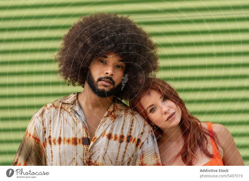 Multiracial couple standing back to back on green background soulmate relationship fondness bonding girlfriend portrait model studio afro curly hair hairstyle