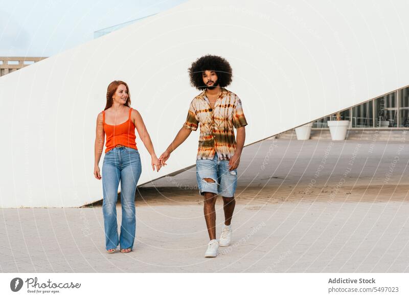Multiethnic couple holding hands while walking love together bonding romantic relationship date amorous boyfriend girlfriend smile happy positive young diverse