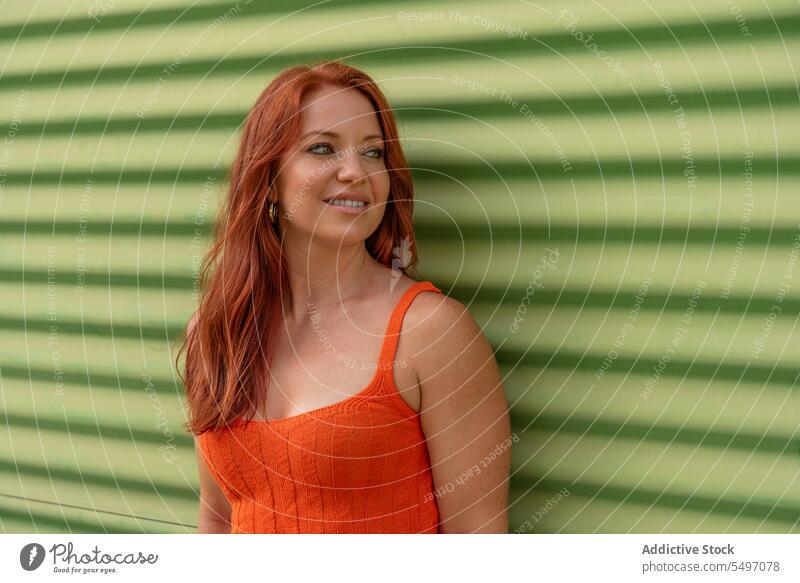 Smiling woman with long red hair looking away smile positive model ginger happy young long hair optimist carefree redhead wall cheerful female glad casual