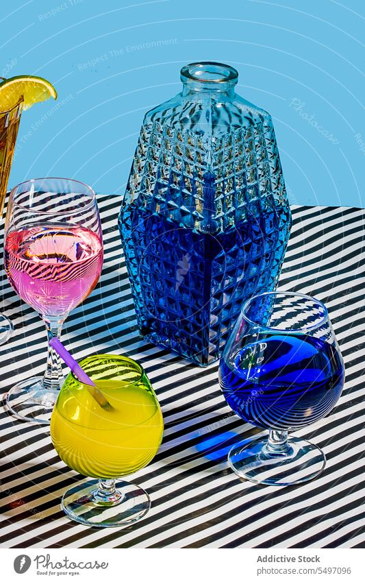 Variety of glasses with various cocktails placed on stripes surface beverage drink blue lemon cold refreshment tea alcohol jar colorful liquid citrus lemonade