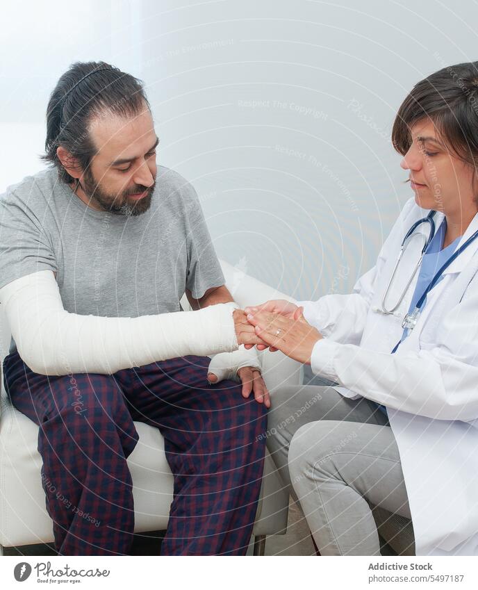 Woman applying antiseptic on injured hand of man woman nurse patient wound antibiotic bandage injury broken arm female orthopedic doctor trauma bruise scratch