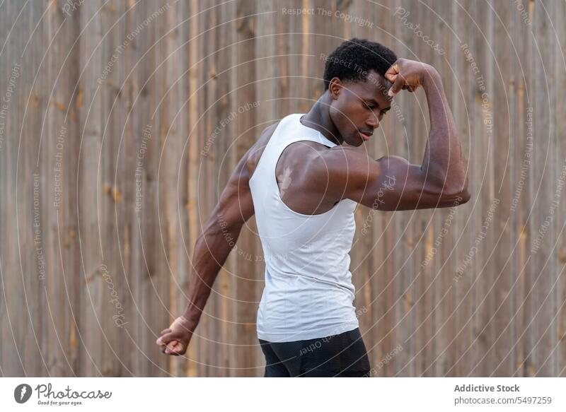 Strong black male athlete showing muscles on street man bodybuilder bicep strong muscular confident training power strength sportsman young african american