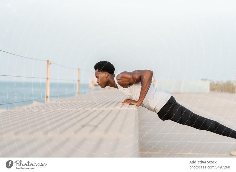 Black man doing push ups on embankment sea workout exercise sport sportswear water training male african american healthy effort waterfront activity physical