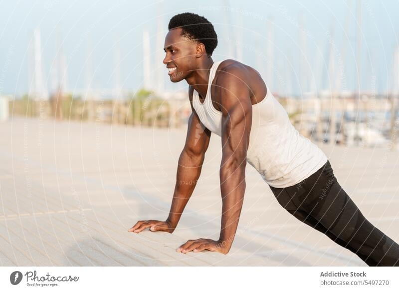 Black man doing push ups on embankment sea workout exercise sport sportswear water training male african american healthy effort waterfront activity physical