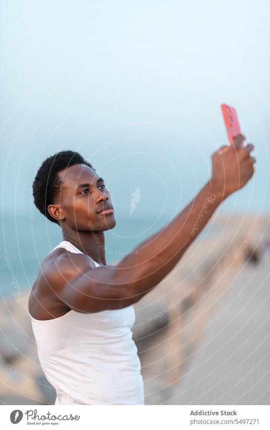 Serious black man taking selfie on smartphone embankment sea positive device male mobile gadget memory take photo enjoy optimist cellphone photography moment