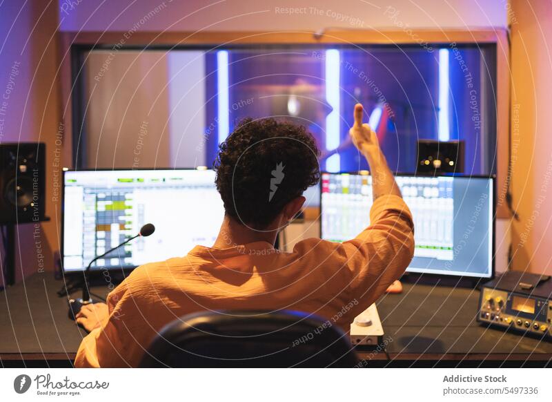 Man approving while recording vocal sound in studio audio engineer singer song music thumb up performer voice technician create produce mixer equalizer panel