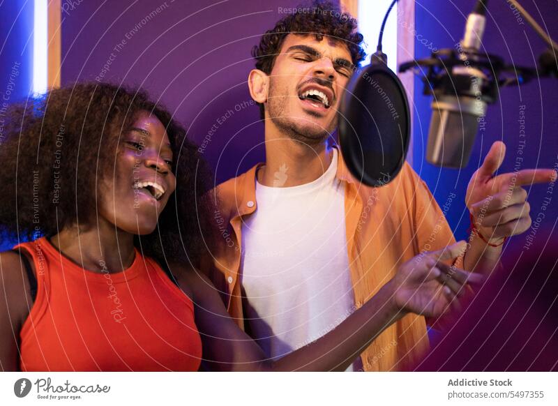 Man and black woman singing and recording song together vocalist write music high note microphone studio point african american professional singer star