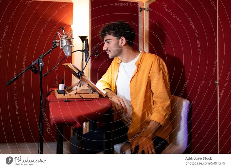 Cheerful young ethnic man sitting and recording podcast with microphone in studio radio host broadcast smile positive male hispanic equipment live job content