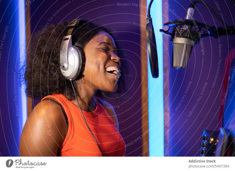 Black woman singing and creating song vocalist record create high note microphone headphones music studio female black african american professional singer star