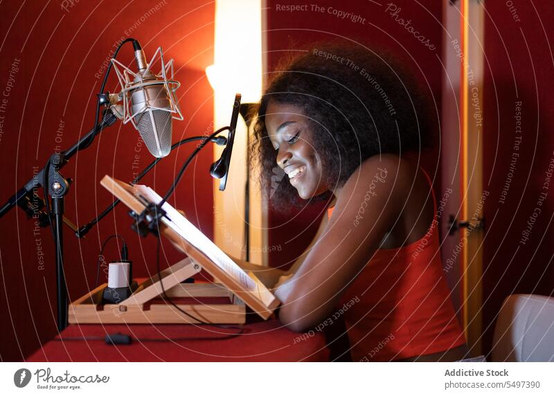 Smiling young black woman sitting at desk and recording podcast host broadcast microphone radio equipment smile studio female african american ethnic audio talk