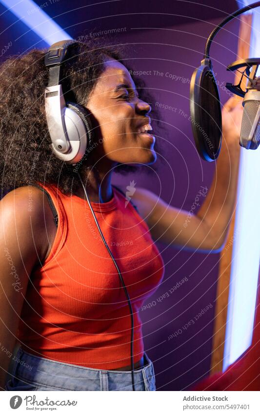 Black woman singing and creating song vocalist record create high note microphone headphones music studio female black african american professional singer star
