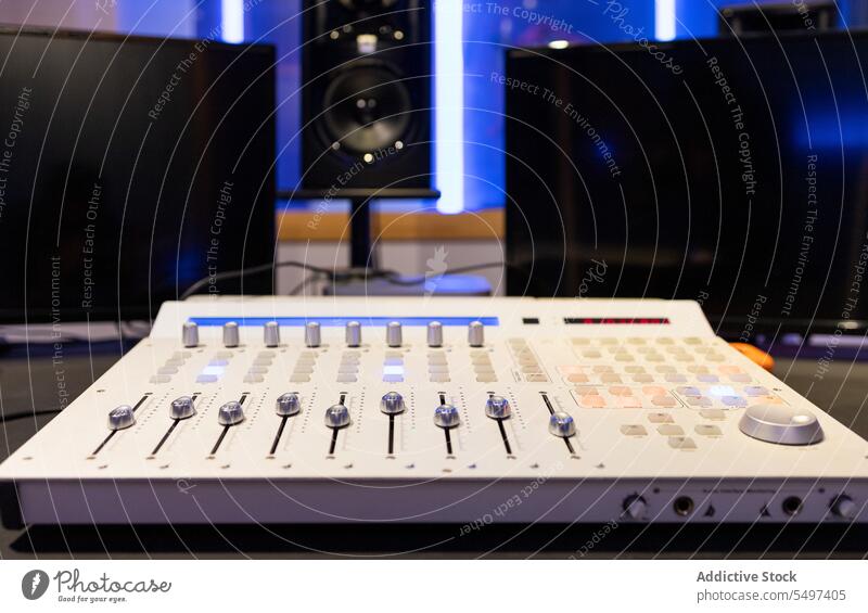 Audio DAW controller station with knobs in studio near blurred interior audio mixer electronic sound console music digital panel device equipment modern gadget
