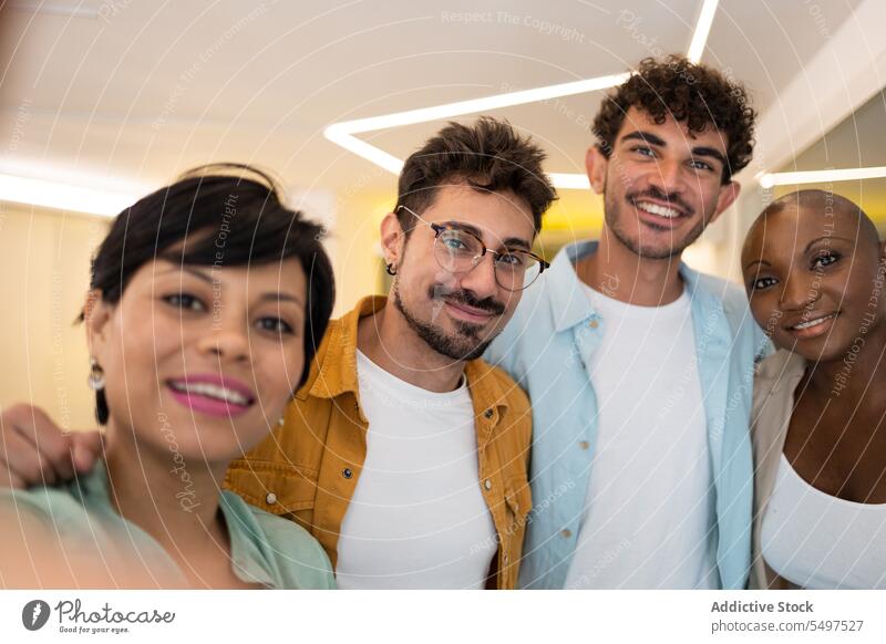 Cheerful multiethnic friends standing in office and taking selfie together group colleague team smartphone smile positive cheerful male female young diverse