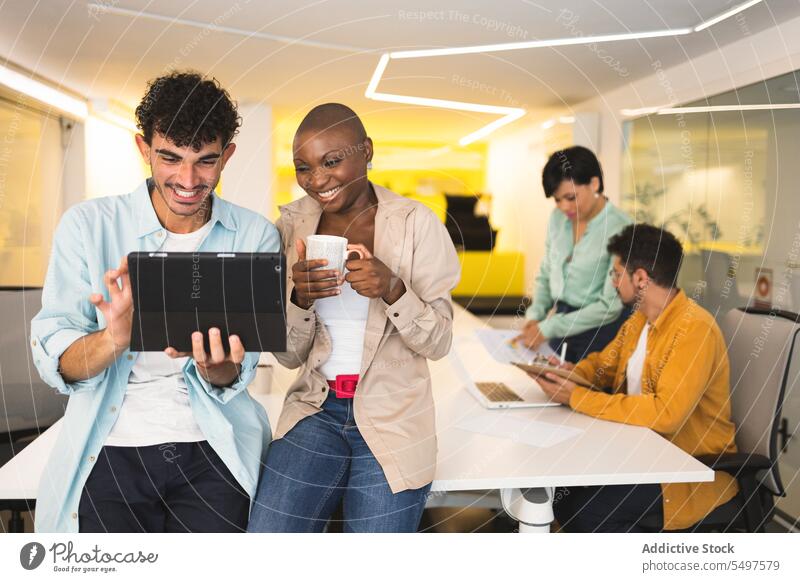 Diverse happy colleagues using tablet together office work laptop smile gadget diverse cheerful browsing device multiracial coworker multiethnic business