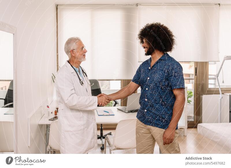 Smiling doctor and patient shaking hands men handshake hospital health care clinic smile cheerful greeting male medical elderly medicine specialist positive