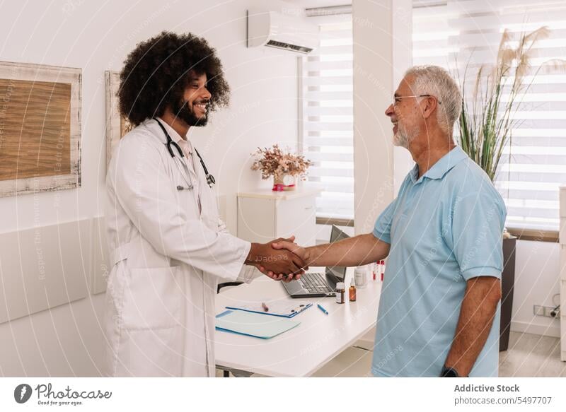 Cheerful diverse doctor and patient shaking hands men handshake hospital medical cheerful smile happy clinic male professional specialist medicine job physician