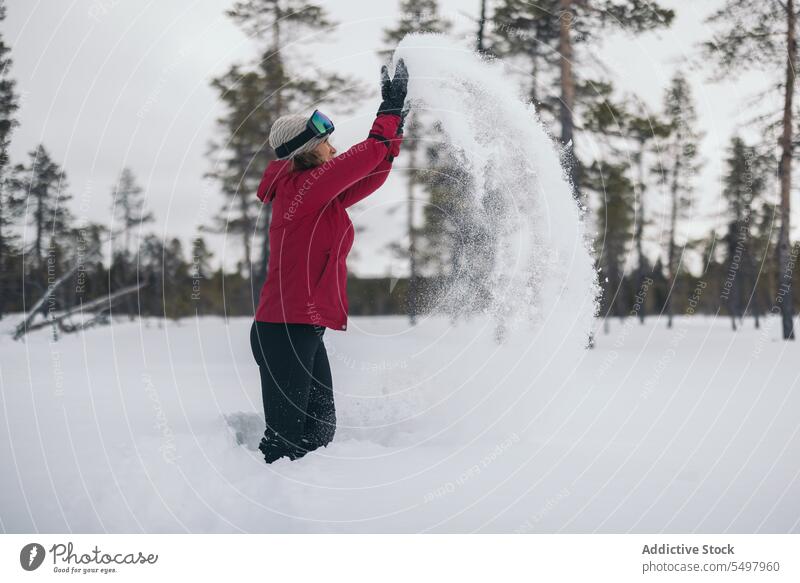 Unrecognizable woman playing with snow winter throw cold tree outerwear nature season female weather wintertime activity environment having fun lapland playful