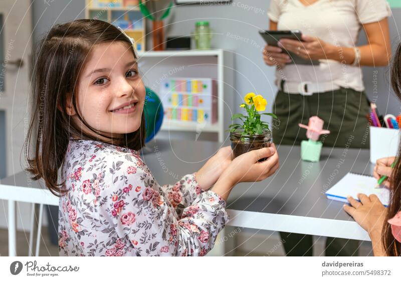 Female student looking at camera while holding a pansy plant in ecology classroom female flower portrait happy smiling young botanical botany nature natural