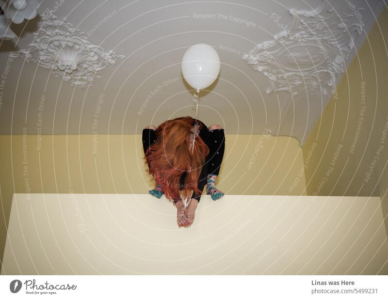 It’s an indoor shoot with a gorgeous red-haired girl with a white balloon in her hands. Surrounded by a vintage background he is sitting in an odd pose. Faceless and colorful. It’s an abstract image with a bit of a moody feeling to it.