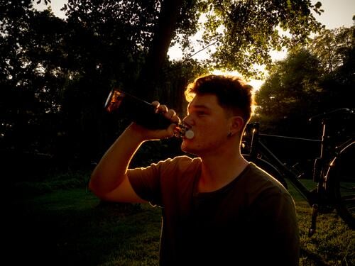 Young man finishes the sunny day with a beer Summer enjoyment Back-light Silhouette Drinking Thirst Alcoholic drinks To enjoy Refreshment Neutral Background