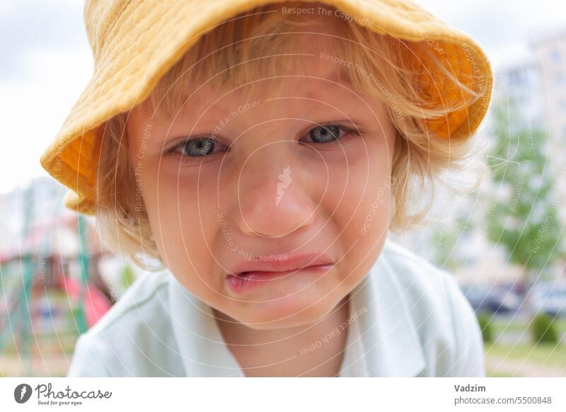 The mood of the child. A small sad boy with a yellow Panama hat cries on the street. Family people children Caucasian To go for a walk 2-4 years old Outdoors