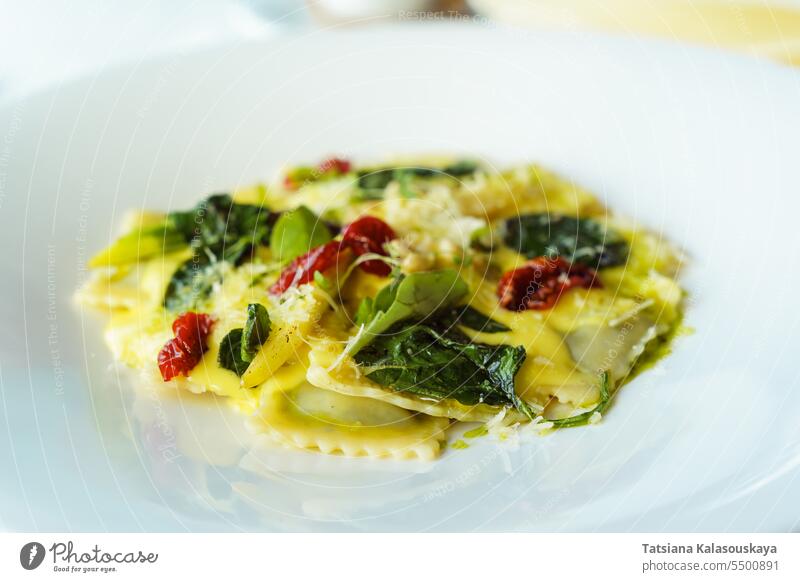 Italian ravioli pasta with basil, spinach, sun-dried tomatoes, pine nuts and cheese in a white plate. Traditional Italian cuisine in the restaurant traditional