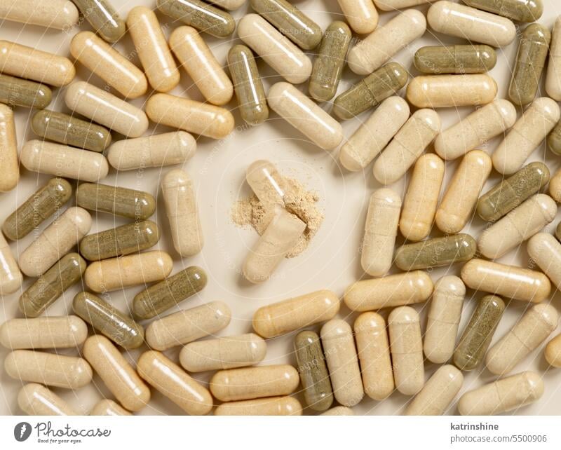 Medical capsules on beige top view. One capsule opened to show a powder. Dietary supplements medicine pharmaceutical pills vitamins antibiotic medical health