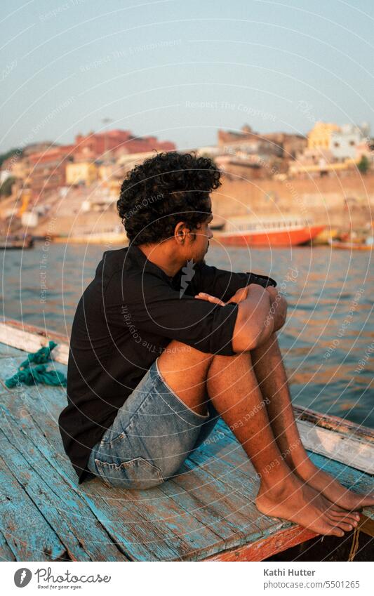 a young man sitting on a wooden boat in varanasi boating Man Water Watercraft Vacation & Travel Navigation Colour photo Exterior shot Tourism Trip Summer