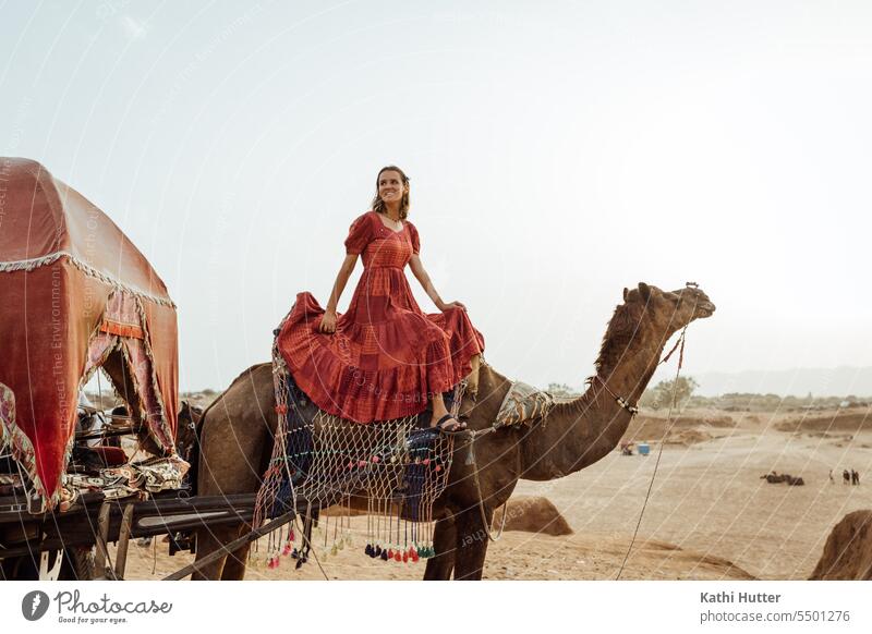a young woman in a long red dress sits on a camel in the desert Woman youthful pretty Young woman Youth (Young adults) Lifestyle Girl portrait Happiness