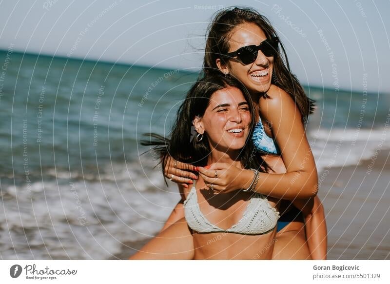 Two pretty young woman having fun on the seaside adult beach beautiful bikini carefree cheerful enjoy enjoyment female friends friendship happiness happy