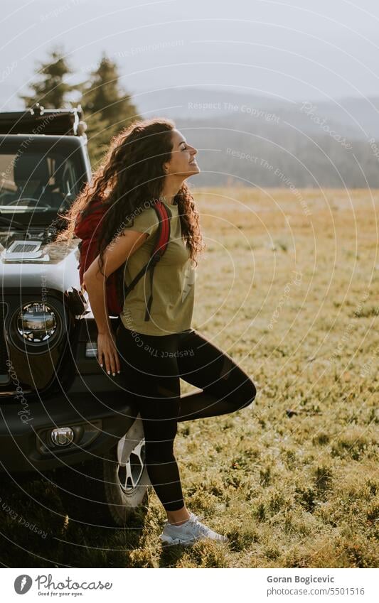 Young woman relaxing by terrain vehicle hood at countryside adult adventure attractive auto automobile beautiful break calm car caucasian day enjoy female