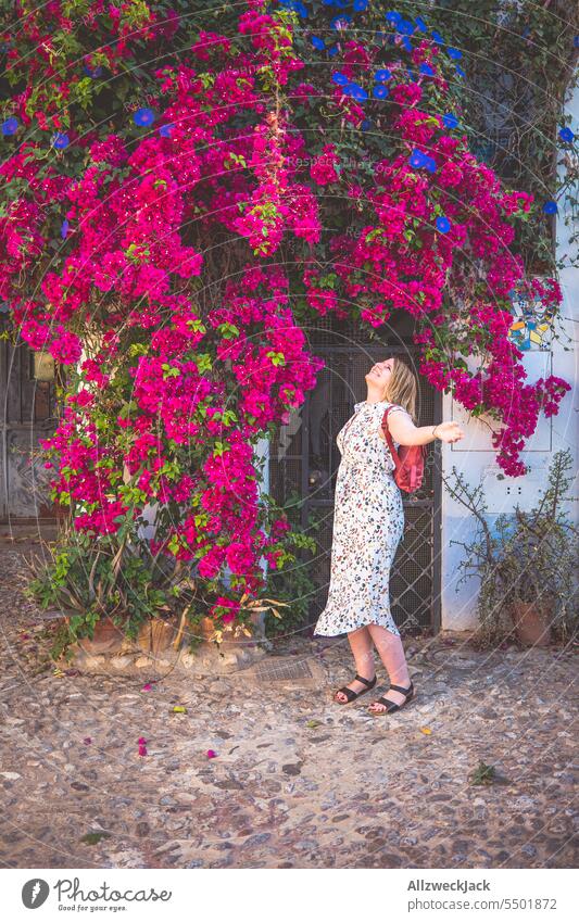 blonde middle aged woman with dress stands under huge purple flowering plant at house in spain Spain Summer Andalucia Granada Bougainvillea Purple Blossom