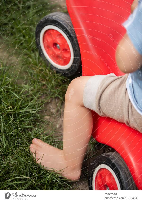 Child on a slide car Toddler Childlike feet Barefoot Playing driven Lawn Meadow out Weather Summer Legs body part play nature naturally Joy Parenting