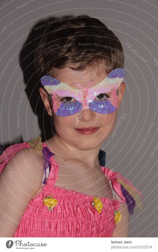 A child in dress and butterfly mask on face over eyes Child Butterfly mask Face Costume Dress Smiling Mask Fairy masculine diversity feminine unisex