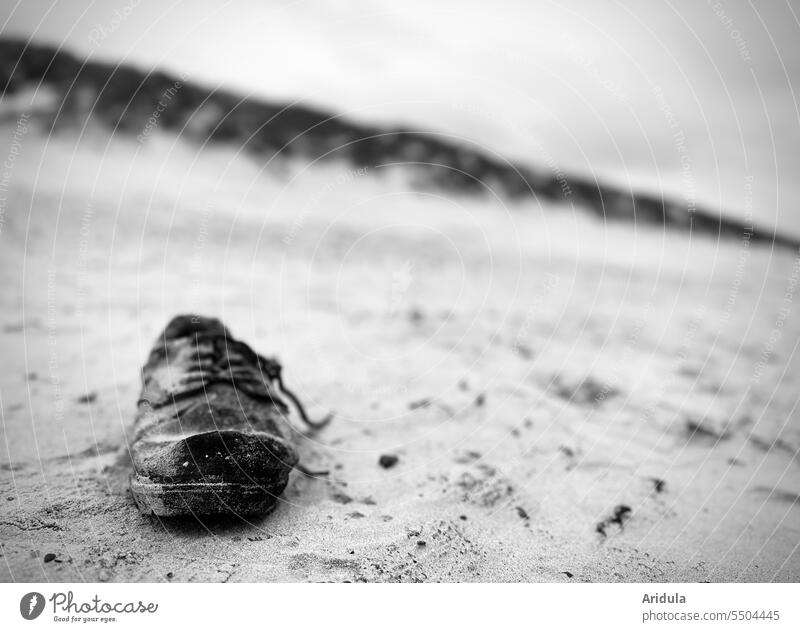 Old black lace up shoe on beach with dune in background b/w lace-up shoe shoelaces Sand Flotsam and jetsam Doomed Beach Black duene Shallow depth of field