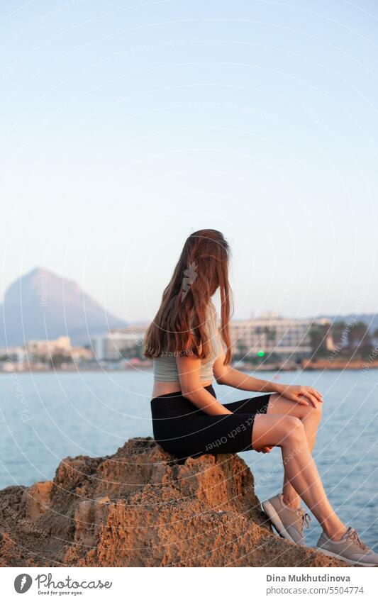 woman sitting on a rock at the beach. Tourist photo. female solo travel. tourist girl island spain mountain rocky landscape coast vacation stone sea ocean