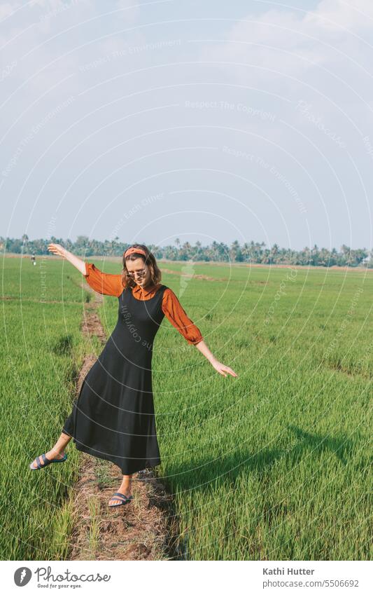 a young woman stands a rice field in Kerala. She wears a black long dress and a red blouse. Woman youthful Modern pretty person Girl portrait more adult Model