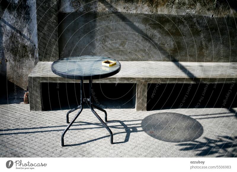 round table with ashtray at industrial cafe in the morning yellow no people circle object outdoor design glass metal background closeup shadow smoking chair