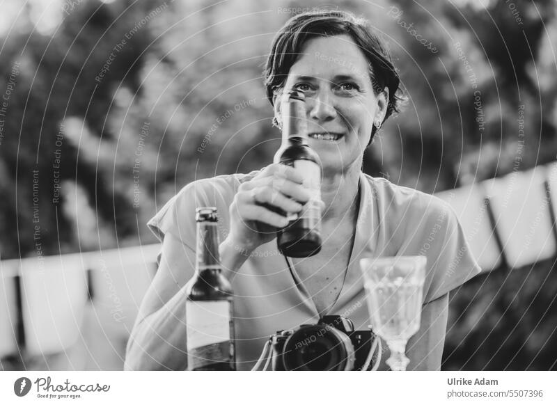 Drinkje bej Inkje | The hostess says "Cheers" - woman looks into the camera smiling and holds up a bottle of beer portrait Face of a woman Head Exterior shot
