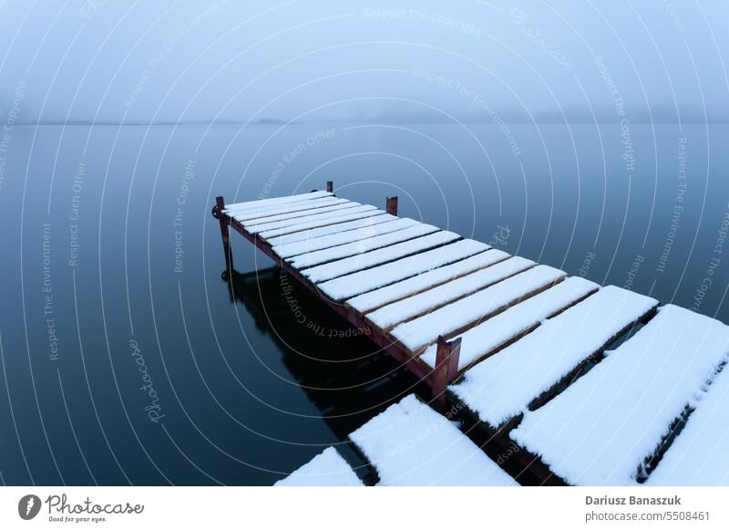 Snow-covered pier on the lake on a foggy day blue weather nature sky water background season snow winter white cold landscape view frost snowy beautiful scene