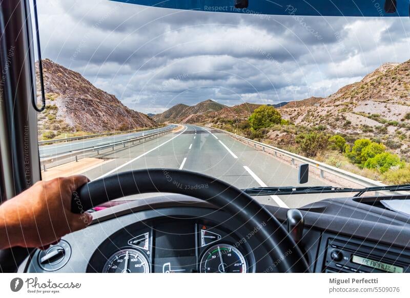 View from the driving position of a truck of the highway and a mountainous landscape. inside road steering wheel transport countryside mountains outdoor trip