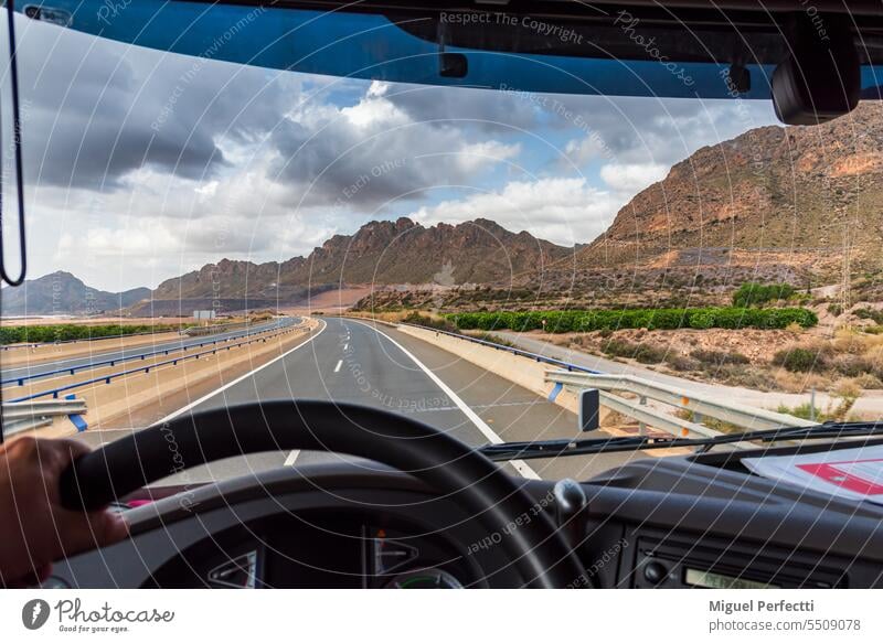 View from the driving position of a truck of the highway and a landscape of mountains in the background at dawn. inside road steering wheel transport